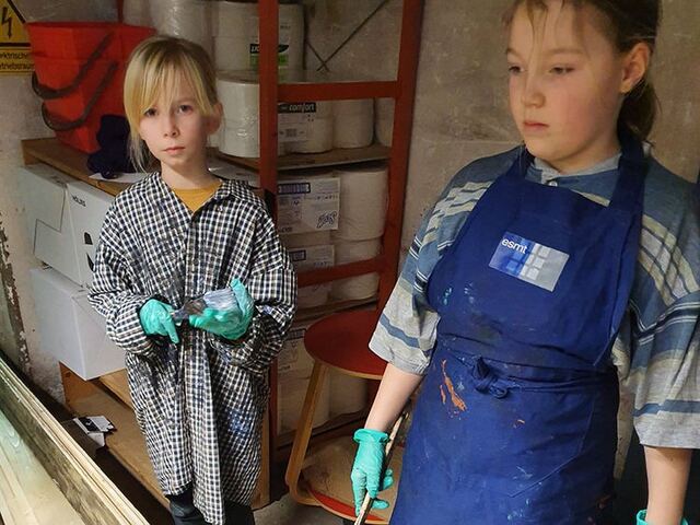 Kinder in Schürzen in der Werkstatt